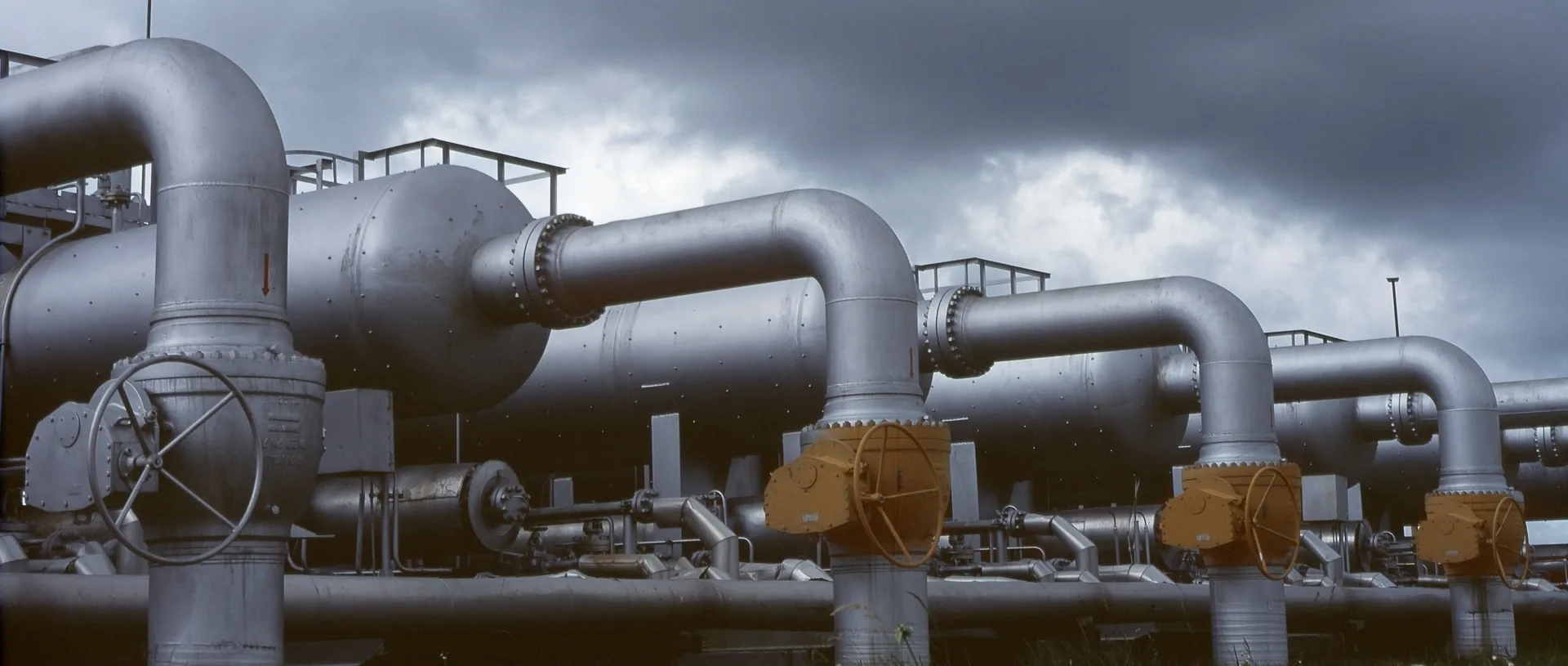Large steel process pipes with elbows, flanges and gate valves at an industrial plant
